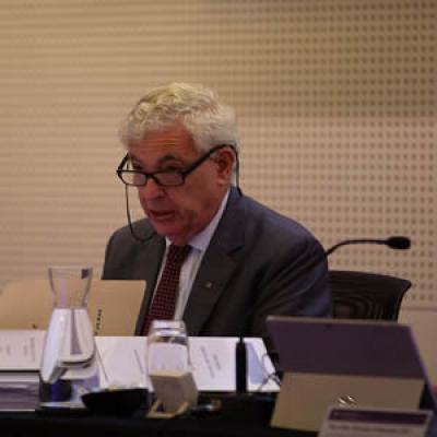 The Honourable Ronald Sackville AO QC sitting at desk with a microphone