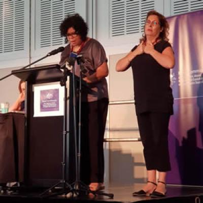 Commissioner Mason and Auslan interpreter standing talking to group of people