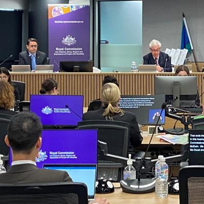 Public hearing 32 with people seated towards two men sitting at a bench